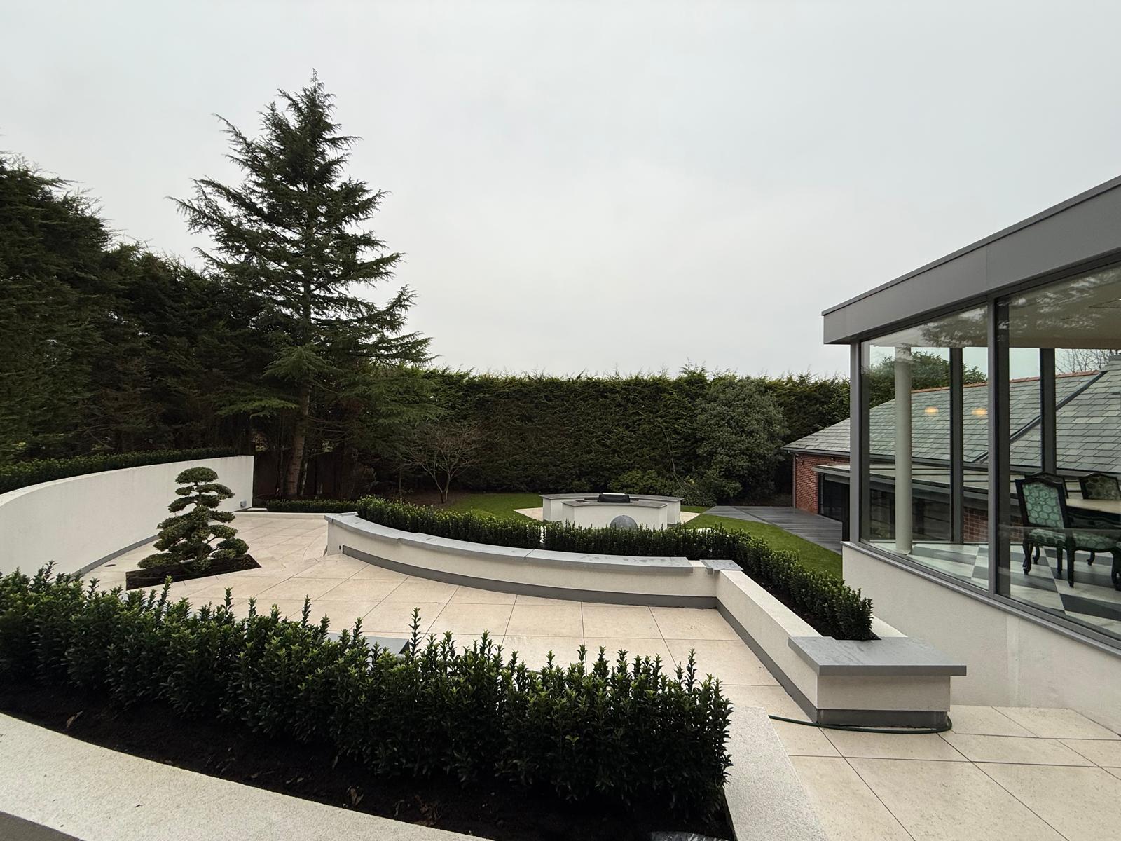 Finished circular garden with rendered curved walls, sunken firepit, water feature and bonsai tree