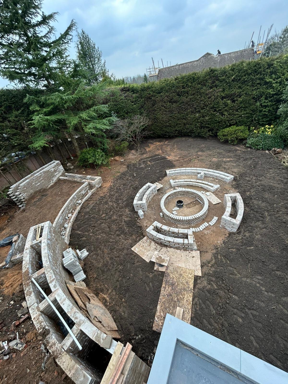 Aerial view of a circular garden firepit and curved walls under construction
