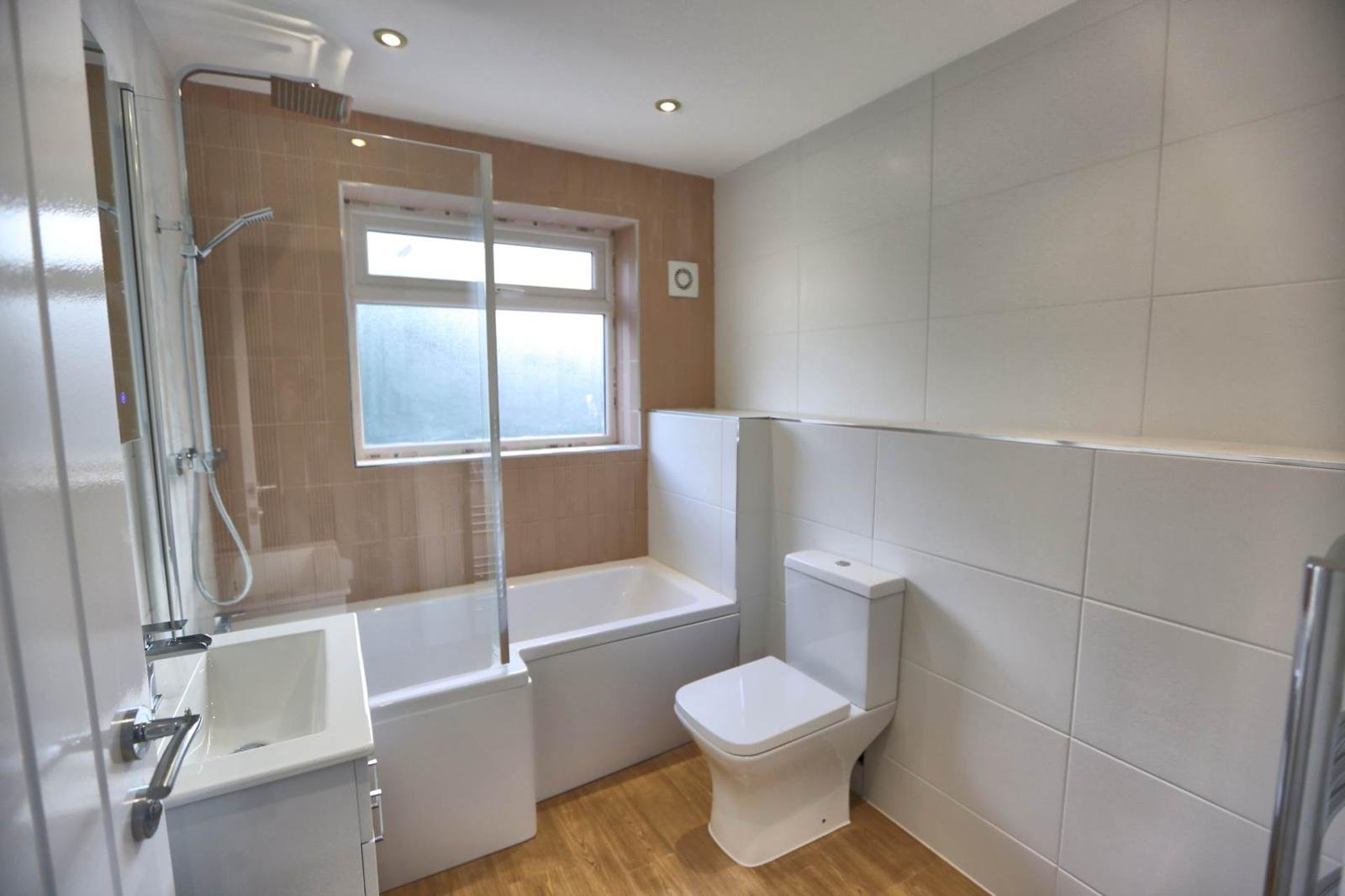 Finished modern bathroom with white suite, full tiling and glass shower screen