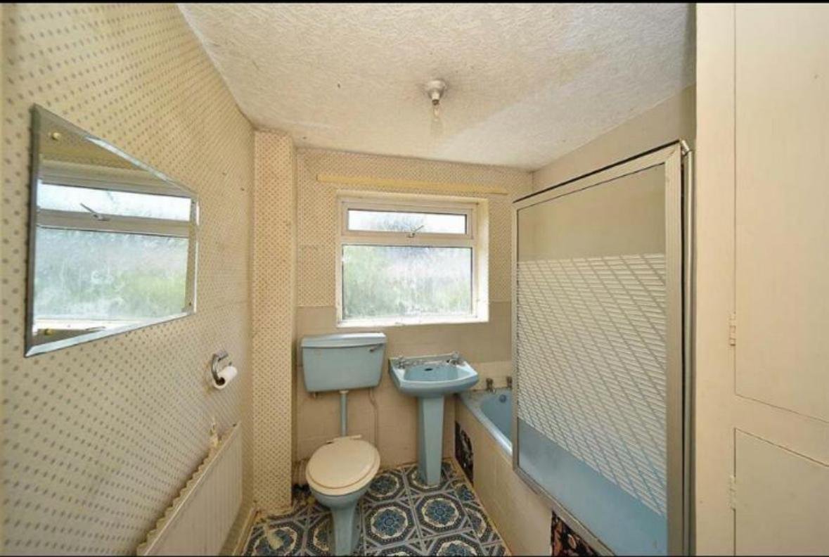 Dated bathroom before renovation with a blue suite and patterned floor