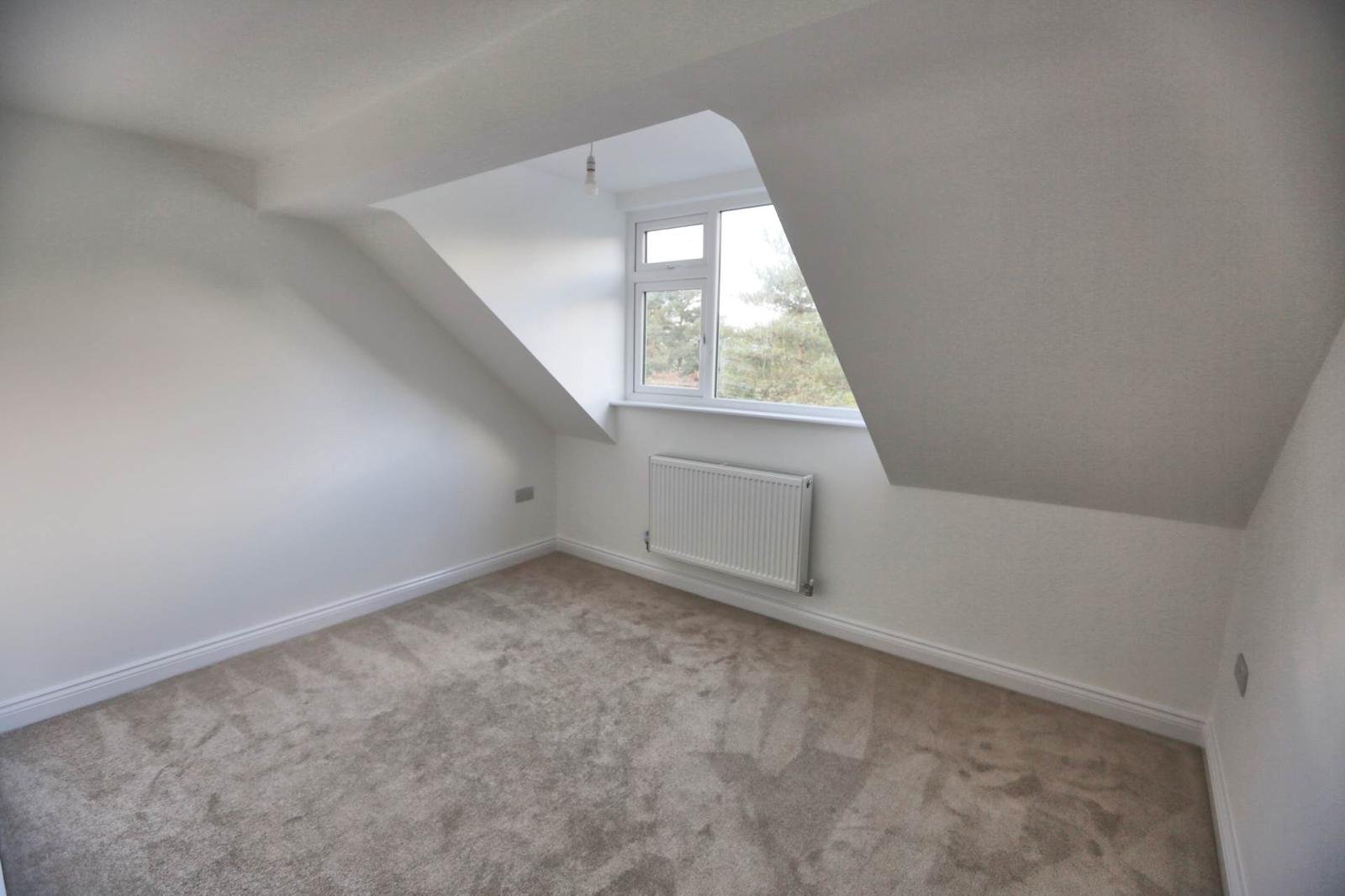 Finished loft bedroom with carpet, fresh plaster and a bright dormer window