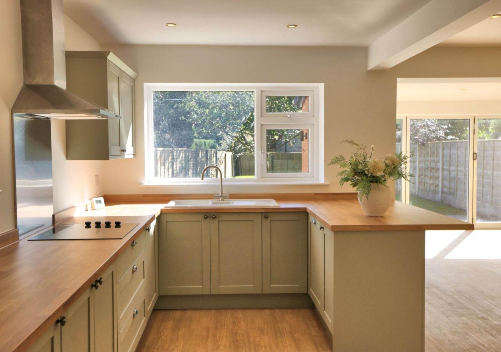 Finished sage green shaker kitchen with wood worktops and open-plan layout