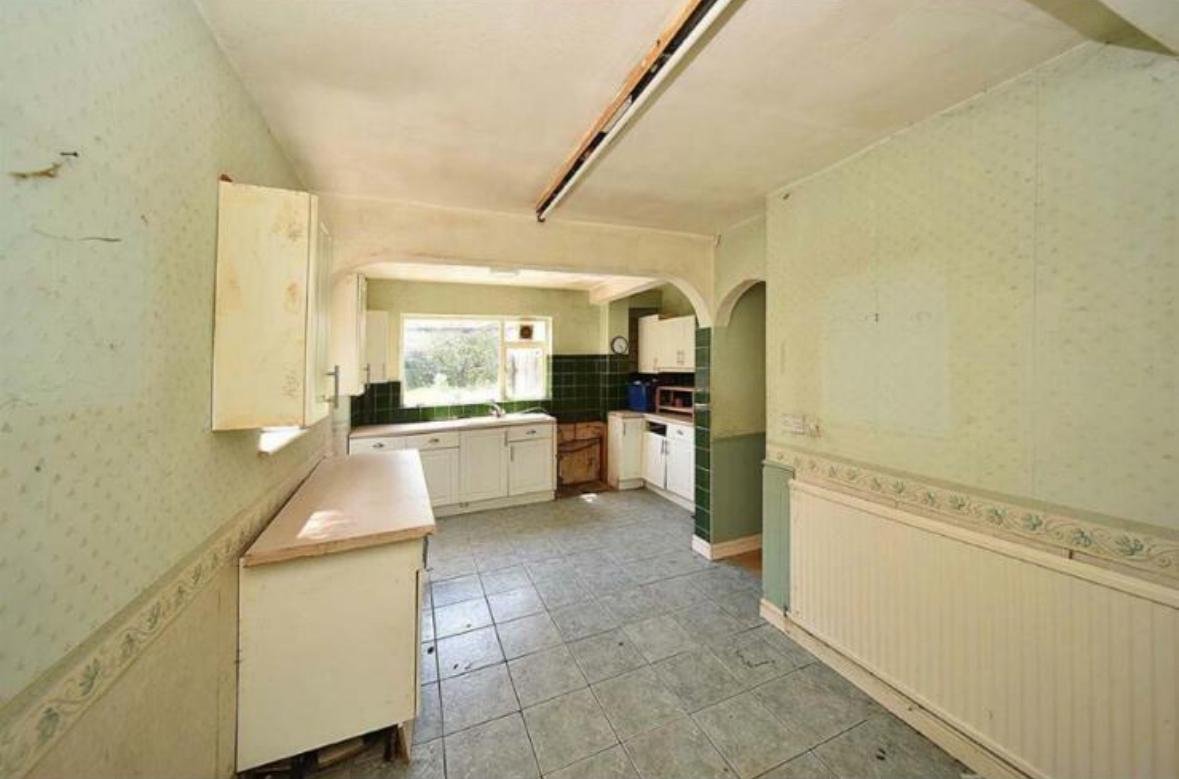 Dated kitchen before renovation with old cabinets and green tiling
