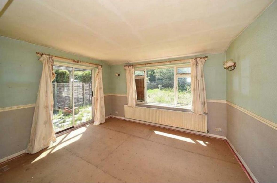 Dated living room before renovation with patterned carpet and old decor
