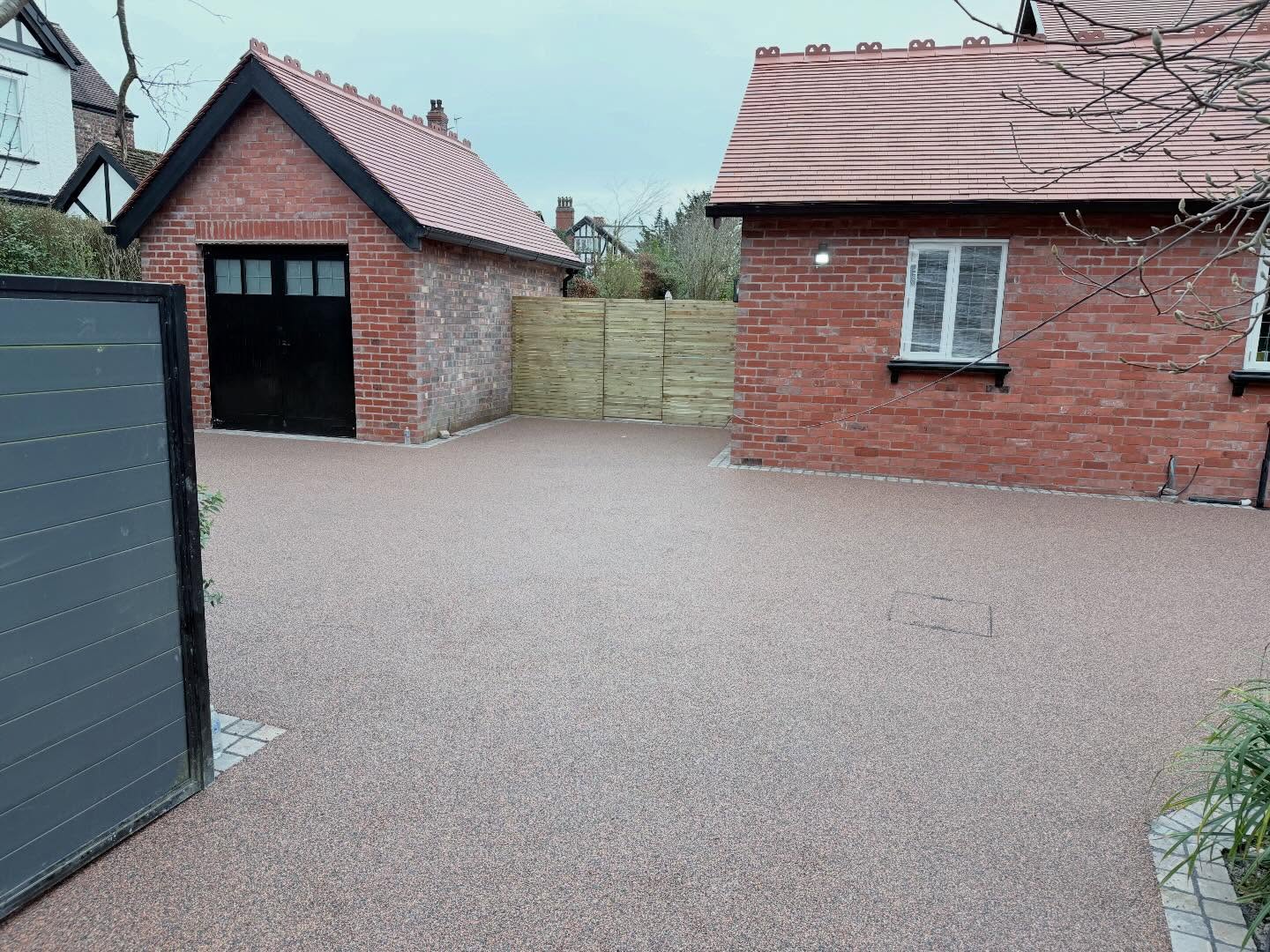 Resin-bound driveway finished in a speckled pink and grey aggregate