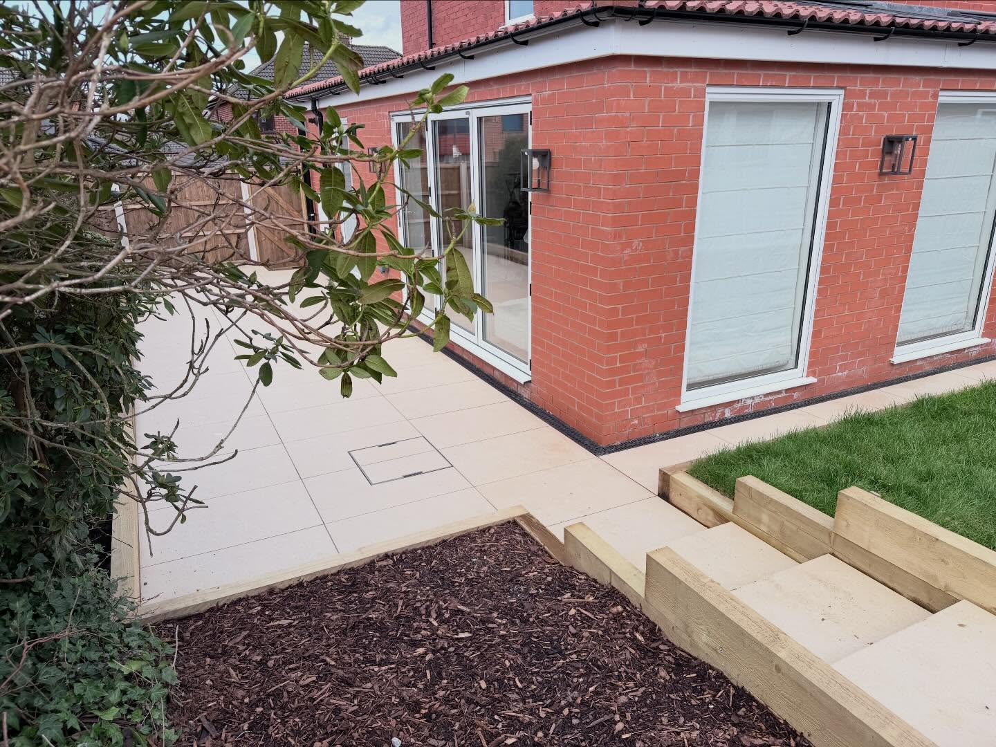 Porcelain patio with sleeper steps down to lawn
