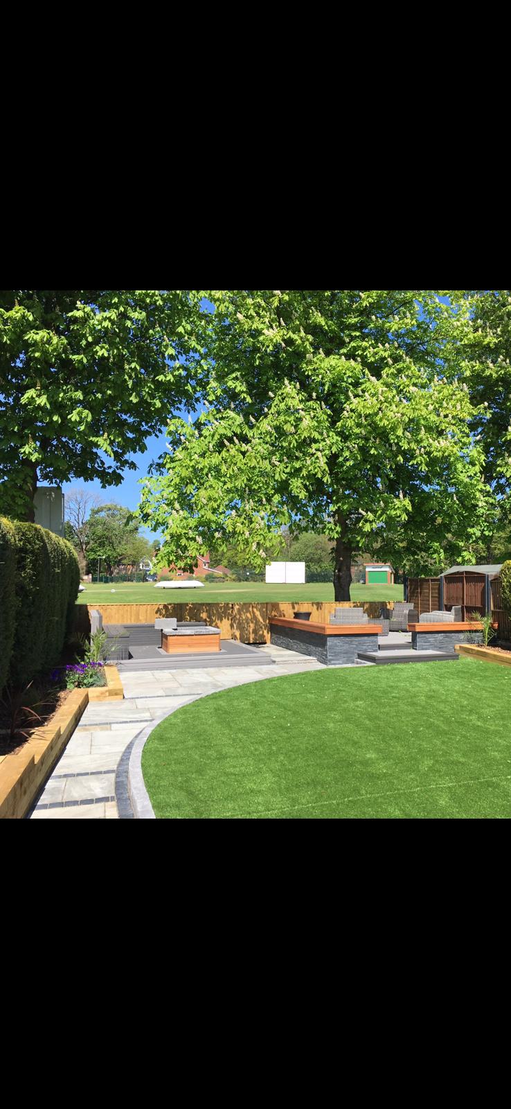 Landscaped garden with artificial lawn and built-in seating area by Pavedway