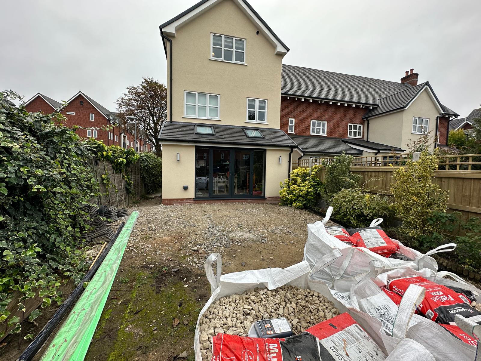 Bare ground with aggregate bags behind an existing extension, before garden renovation