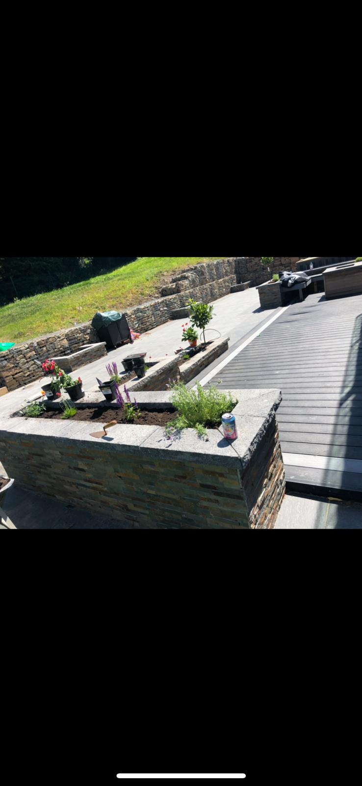 Stone-clad retaining wall with raised planters in a landscaped garden